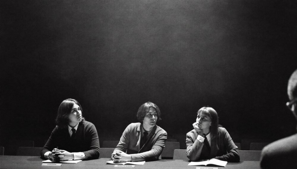 Three judges at a long table in a dark auditorium, listening to a pitch off frame.